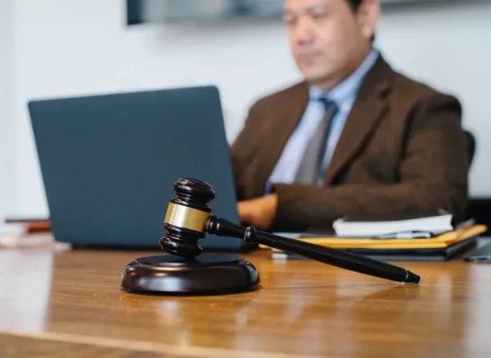 a person working on the background on his laptop with gavel on in the front